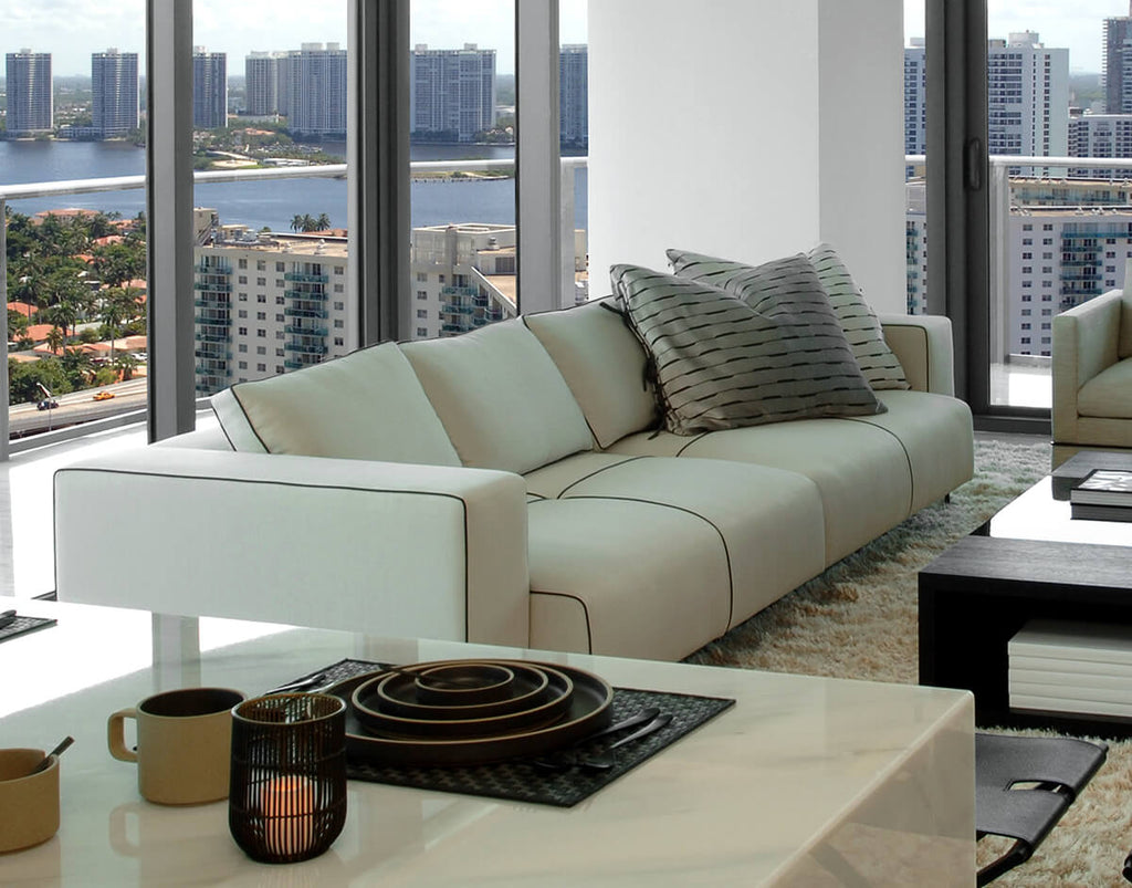 Modern cream-colored Glasgow Sofa sectional with dark piping and cozy throw pillows