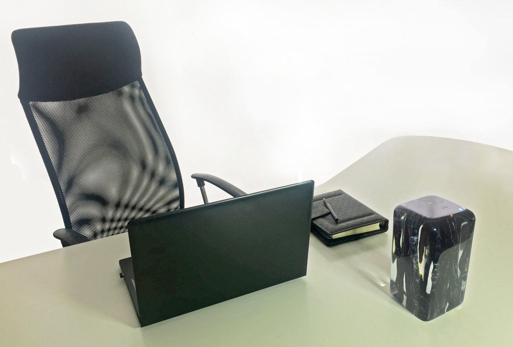 Black office chair with mesh back and laptop on desk in Burnt Branches Cube setting