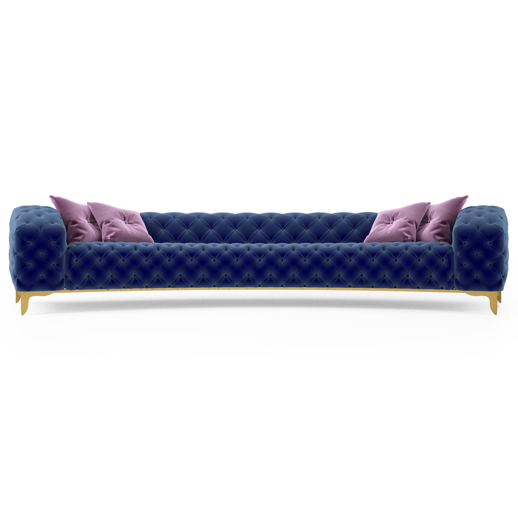 Dark blue tufted velvet curved sofa with pink accent pillows and gold legs