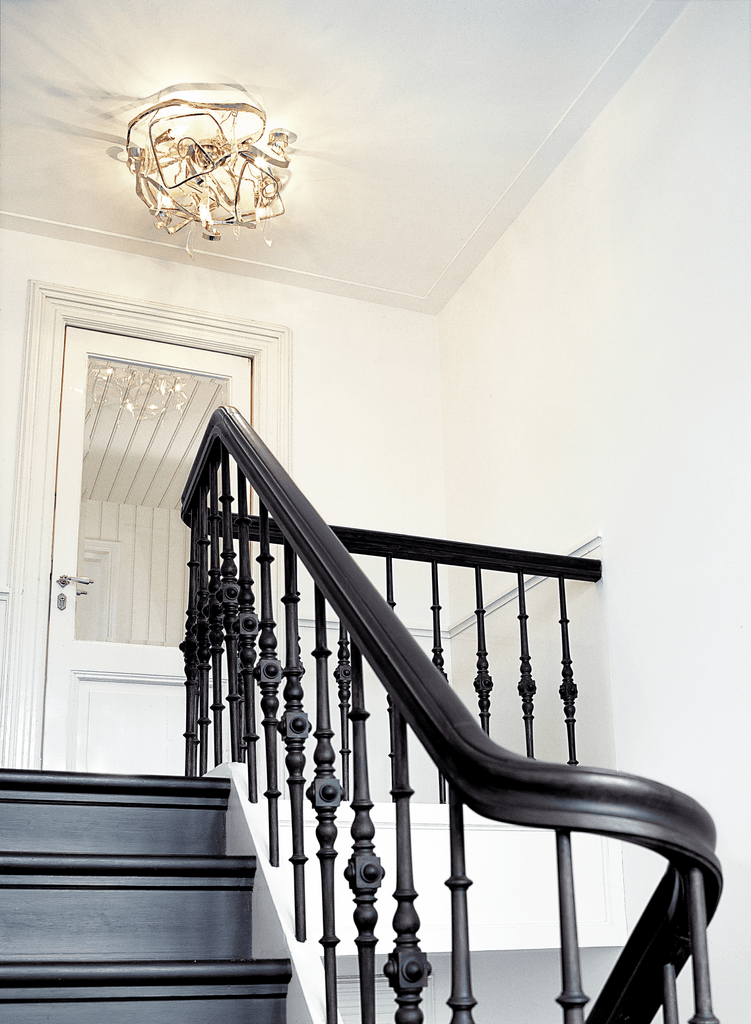 Delphinium Ceiling Lamp Round illuminating a stylish black wooden staircase with ornate balusters