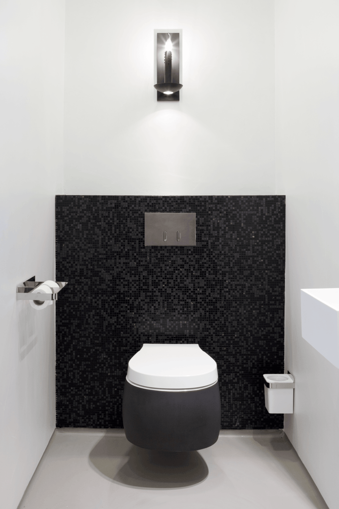 Modern dark grey toilet with white seat against black mosaic wall, ideal for floating candles wall lamp decor