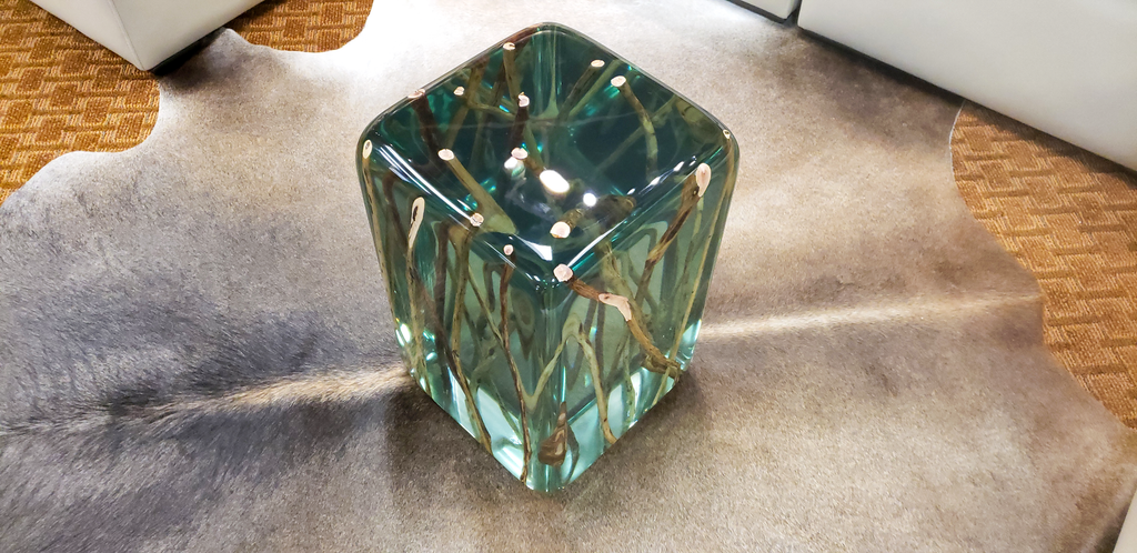 Green branches end table featuring a clear glass cube vase with swirling green and brown patterns