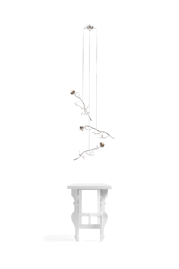 White wooden side table with branch-like vie en rosa rosa single light above