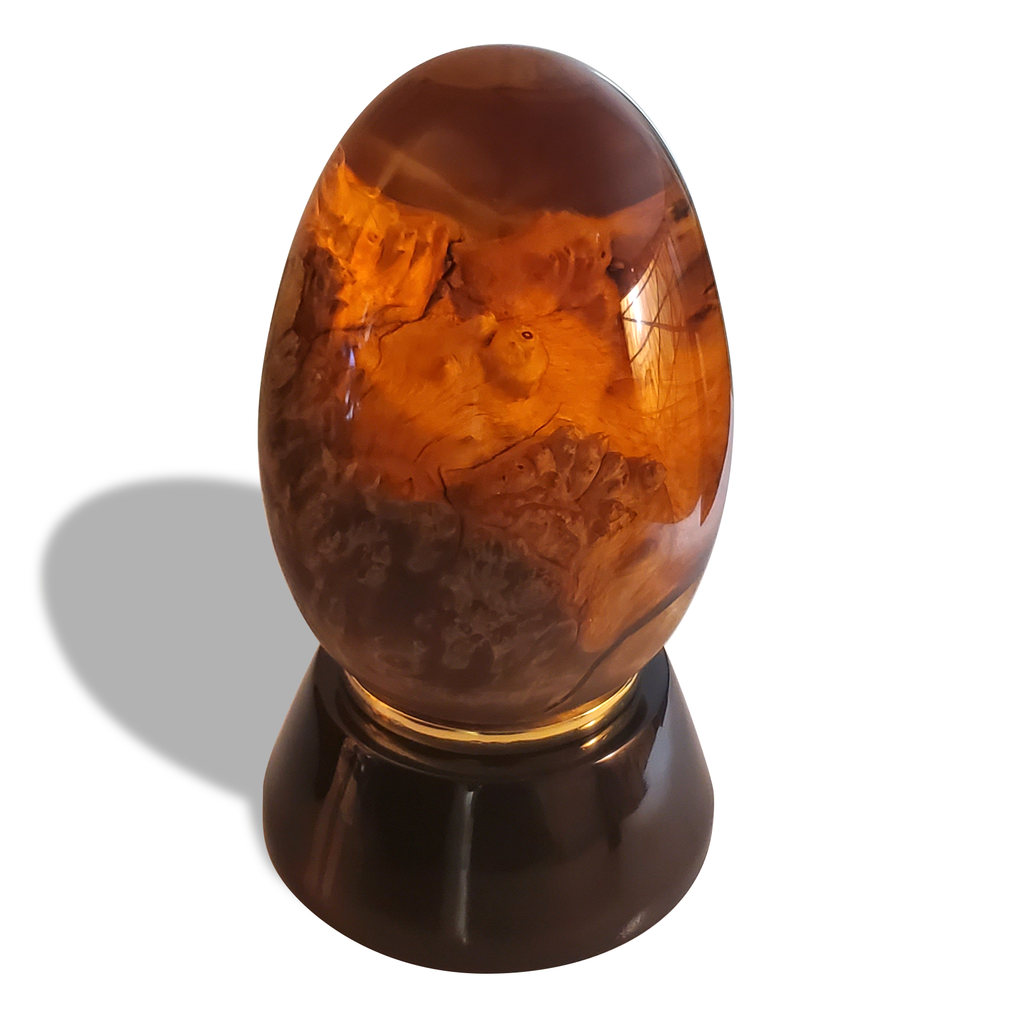 Ornate orange Dragon Egg with amber color on dark brown stand, made of base metal